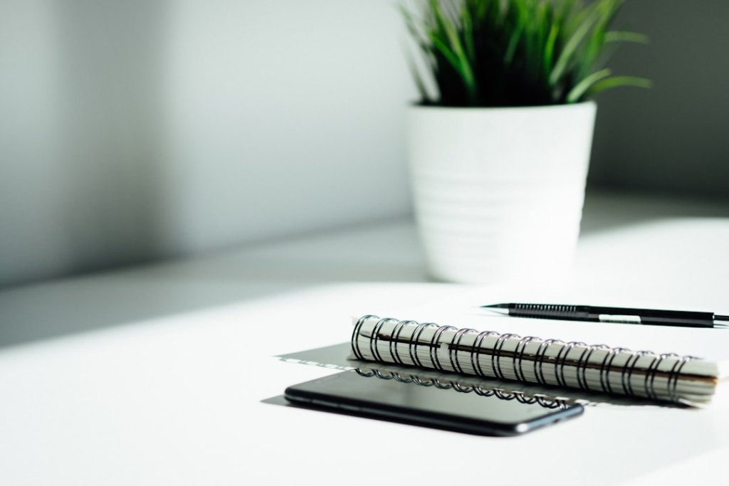 iPhone und iPad auf einem Schreibtisch, verbunden mit einer blauen Schutz-Cloud als Symbol für die Verwaltung mit Intune